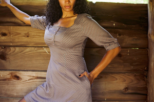 elbow length sleeved Ashland dress worn by a model standing against a wooden wall