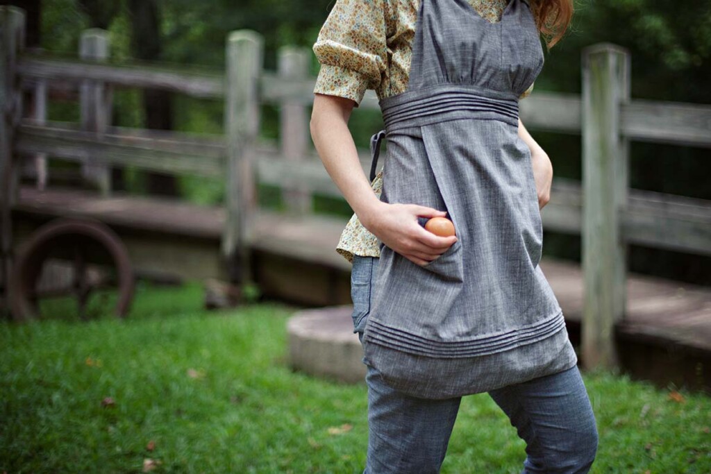 Grey Gathering Apron worn over a floral shirt and jeans
