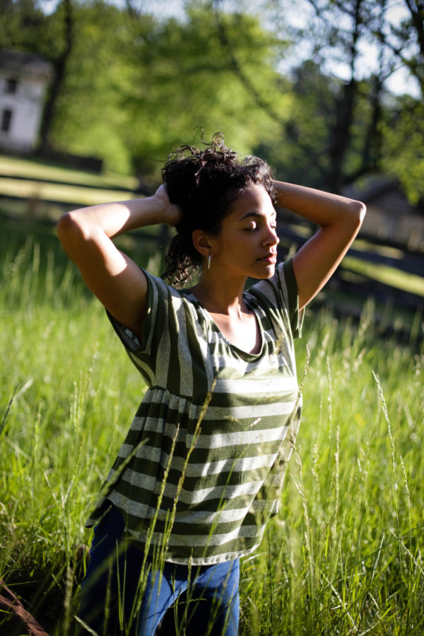 grey and green striped Paloma Top worn by a model standing in a field holding her hair off of her neck