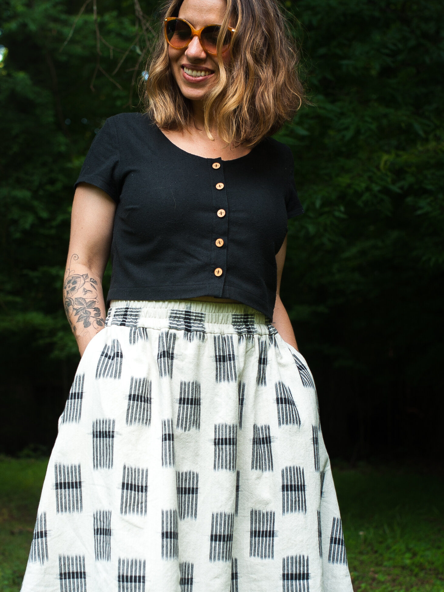 Meg wears a cropped black hinterland top and a black and white printed gypsum skirt in the woods