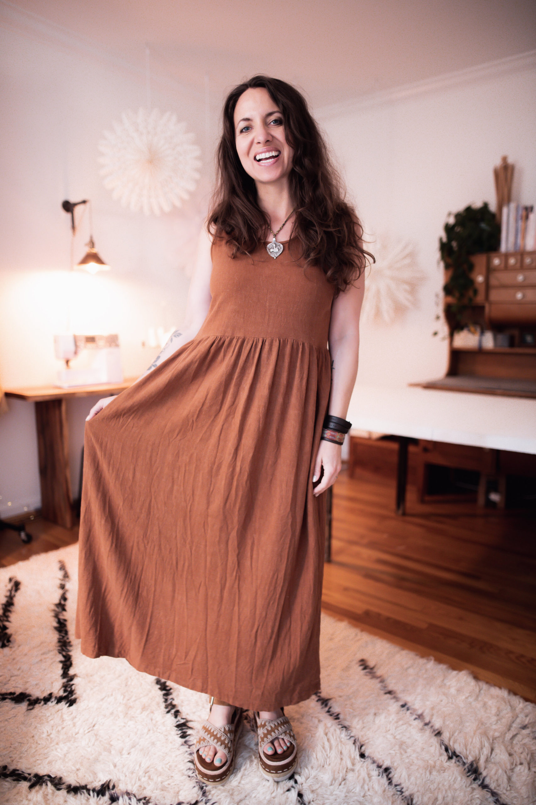 Meg wears a maxi length, placket fredd clay red Hinterland dress and brown sandals