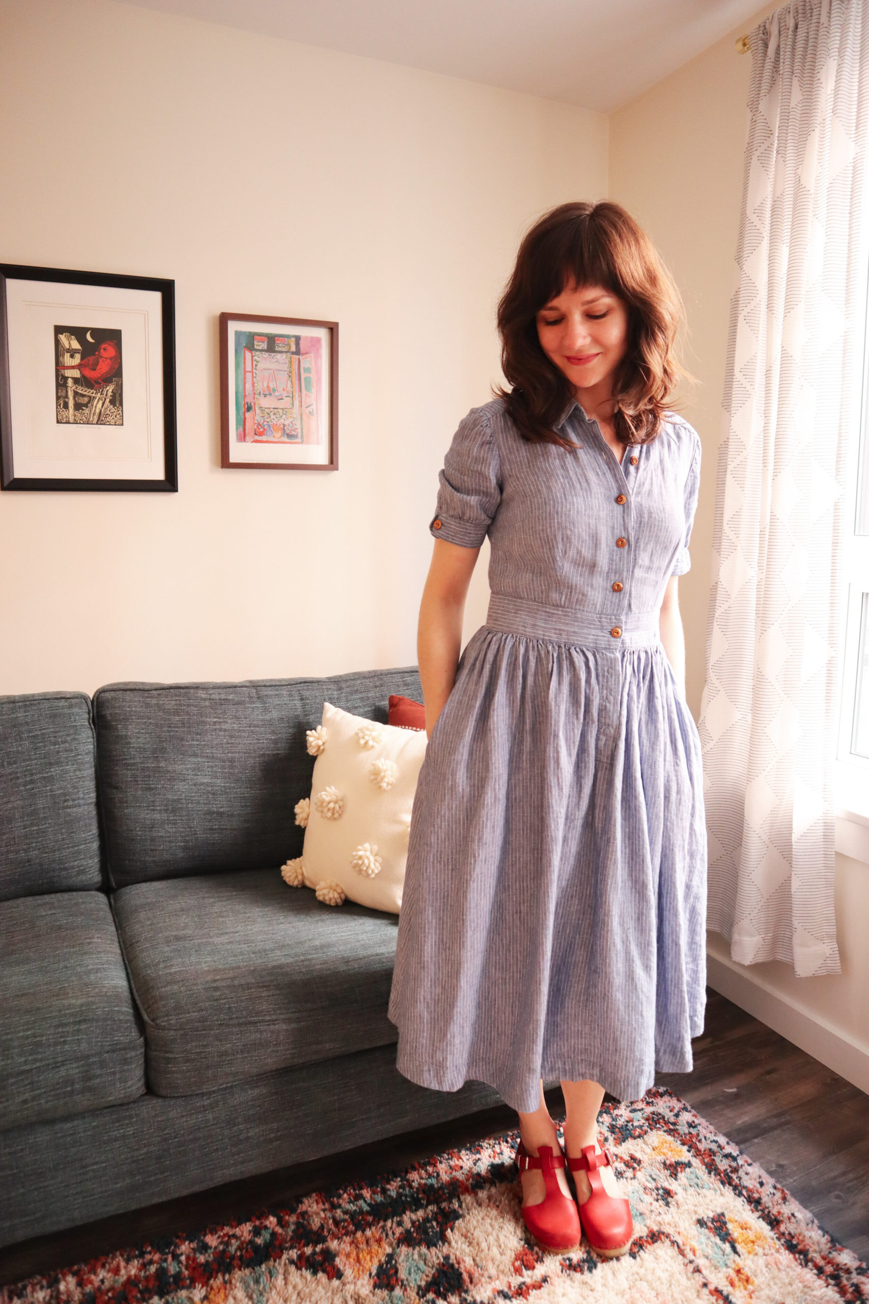 Meredith wears a blue and white pink striped fit and flare shirt dress with red clogs