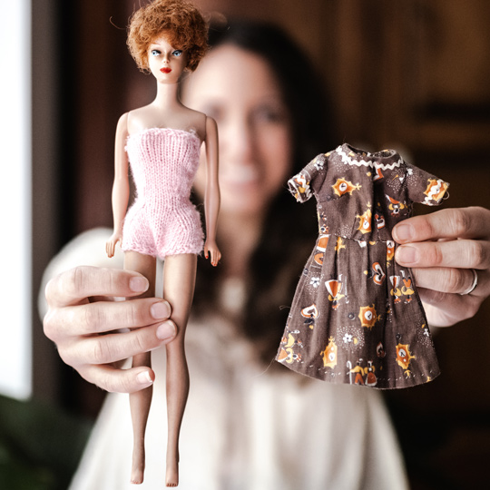Meg holding a vintage Barbie doll with a brown dress made by her great-grandmother