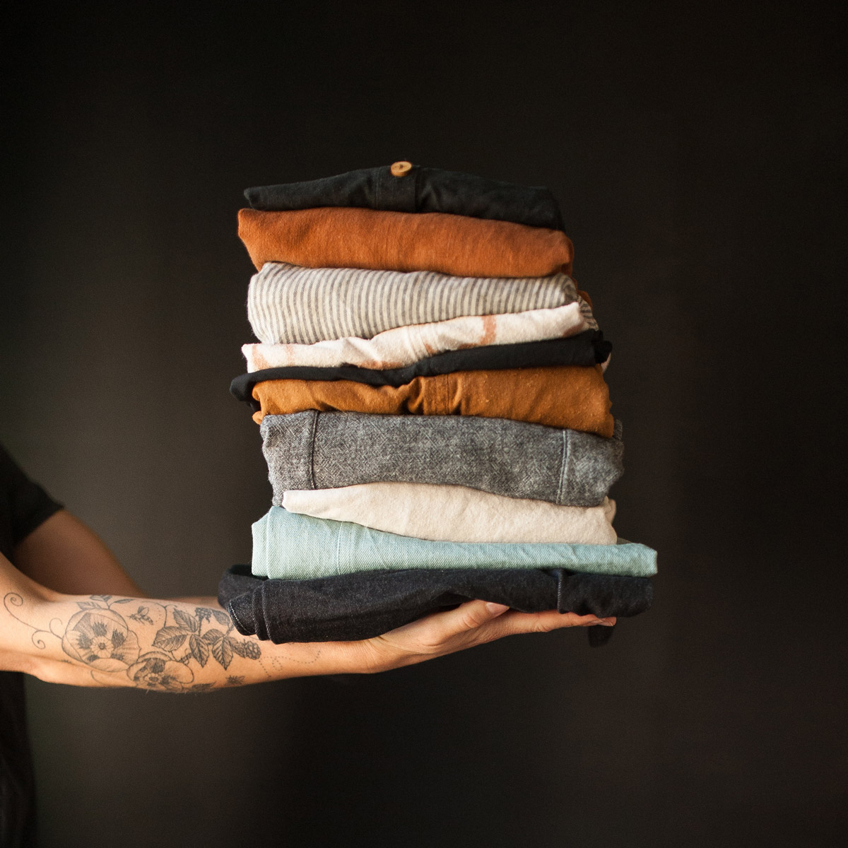 Meg holding a stack of fabric in an oustretched arm.