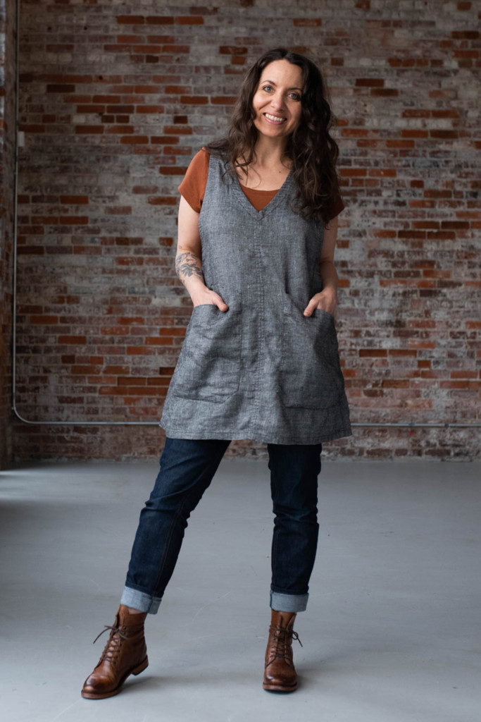 Meg wears a Studio Tunic in front of a brick wall.