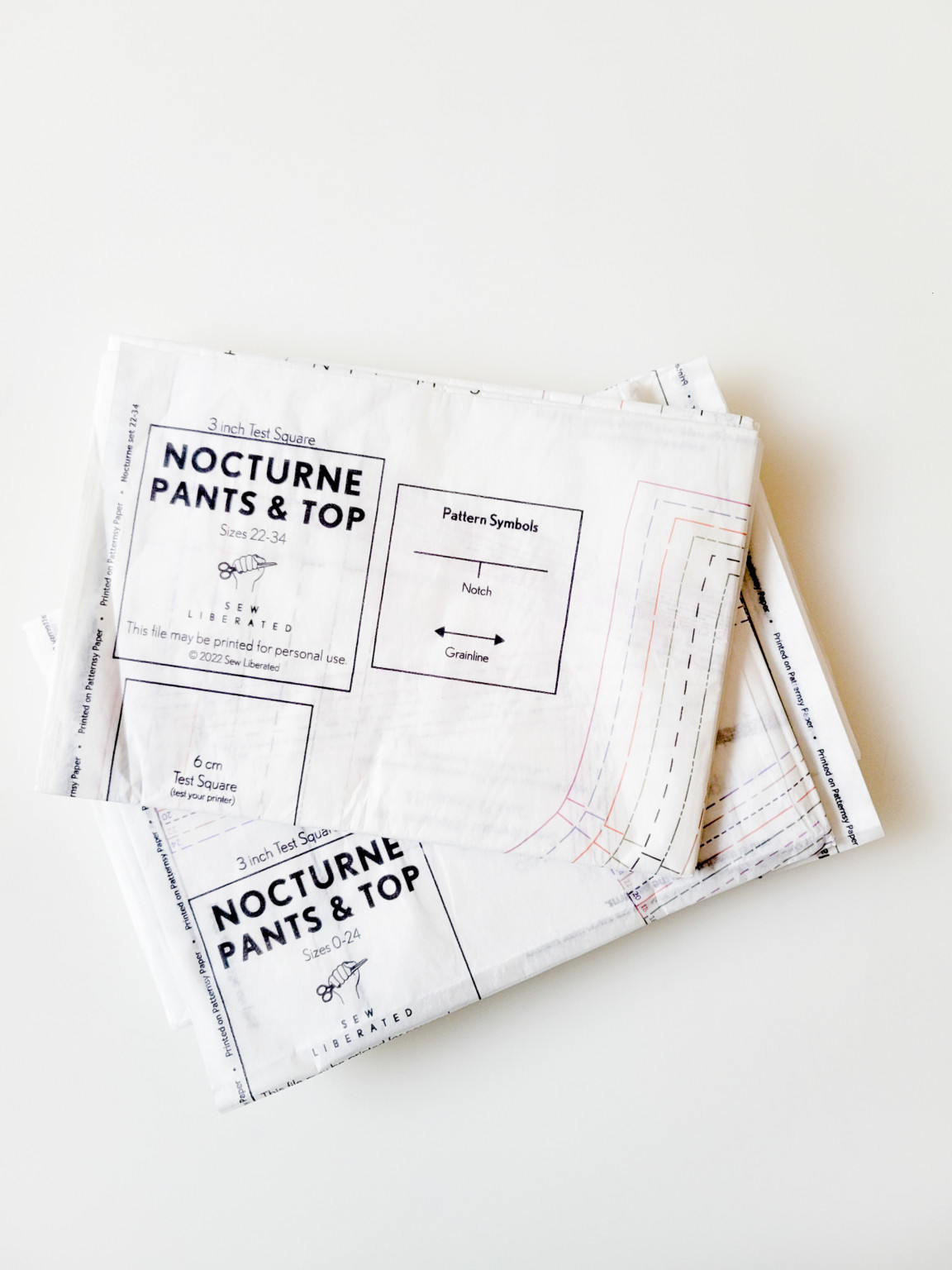 Printed pattern sheets of the Nocturne Pajamas Pattern are sitting on a white table.