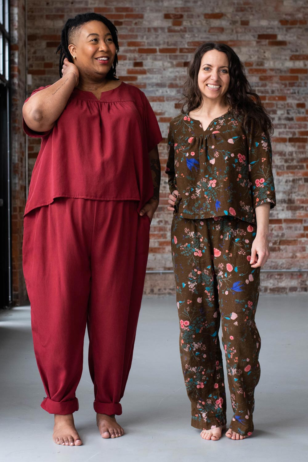 Meg and Ashley wear their Nocturne Pajamas in front of a brick wall.