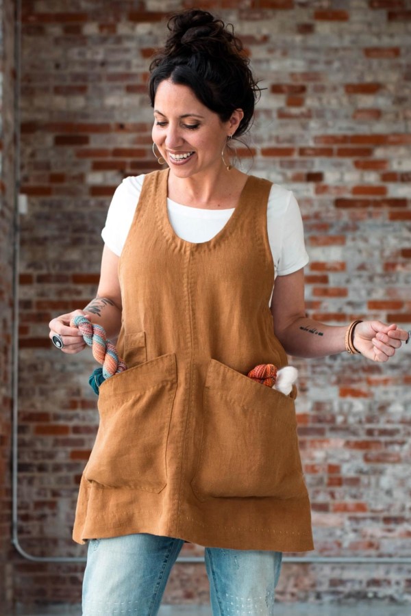 Meg wearing a caramel-colored Studio Tunic, with yarn filling her pockets.