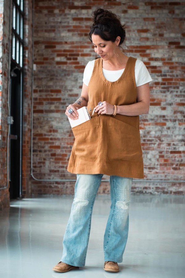 Meg wearing a caramel-colored Studio Tunic, carrying a book in her large pocket.