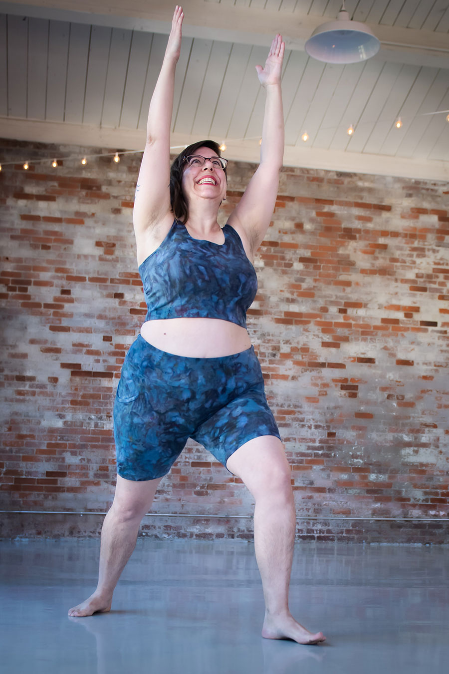 Shaerie does a yoga pose in her blue ice dyed Limestone leggings bike shorts and top