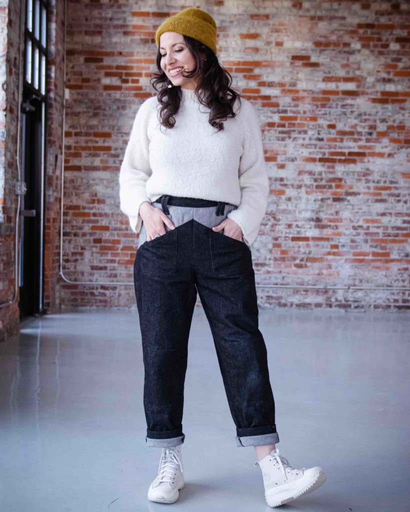 Meg wears the Cosecha Pants Sewing Pattern in black denim with a white sweater. 