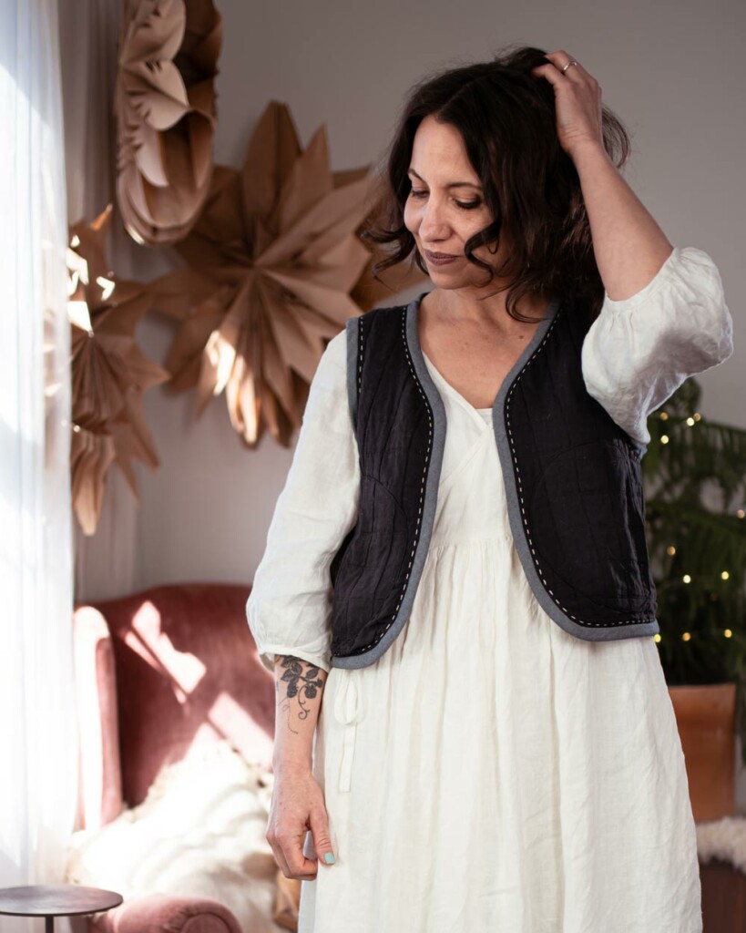 Meg wears her quilted vest Hinterland dress hack. When sewing, she chose black pre-quilted jacquard fabric and a chambray bias binding.