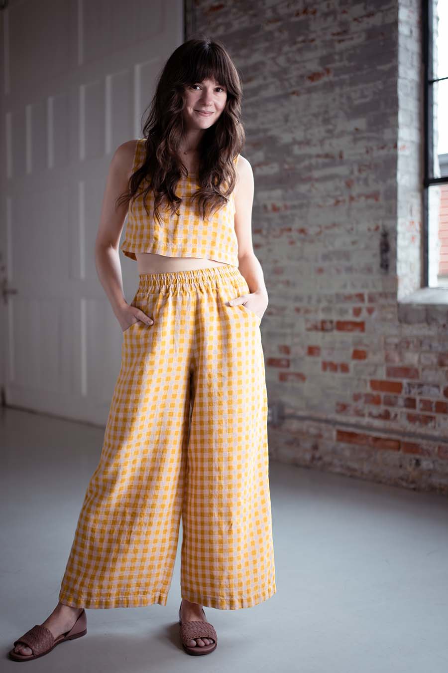 Meredith wears a pink and yellow gingham hinterland crop top and matching chanterelle pants.