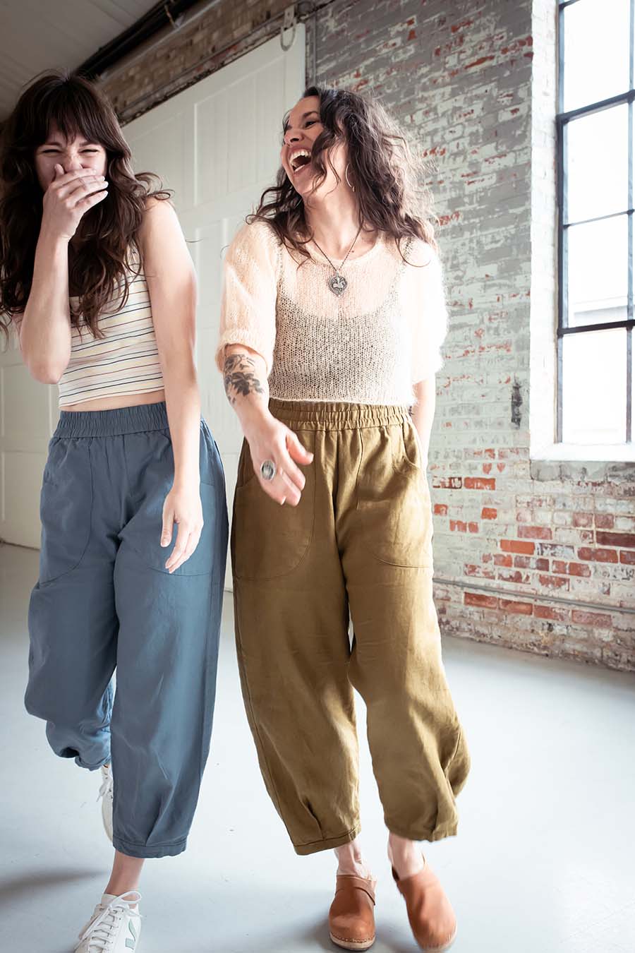 Meg and Meredith walking and lauging. Meg wears olive chanterelle pants and Meredith wears blue ones